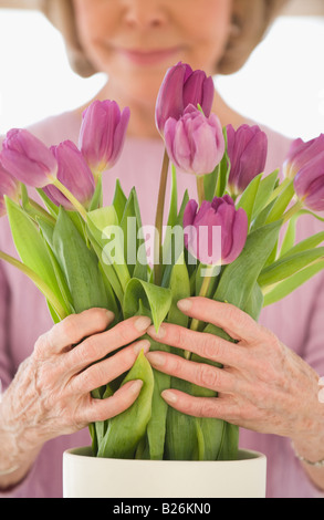 Ältere Frau, die Vermittlung von Blumen Stockfoto