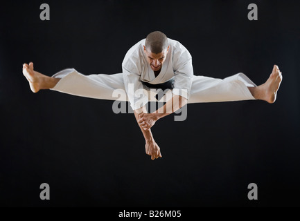 Hispanische männlichen Karate Schwarzgurt in Luft springen Stockfoto