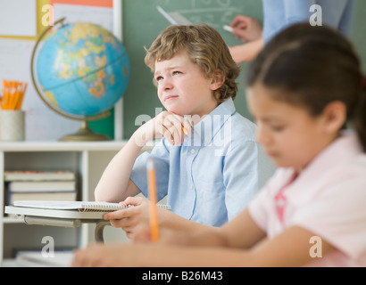 Jungen denken an Schulbank Stockfoto