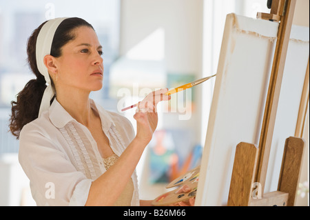 Hispanic Frau malt auf Staffelei Stockfoto