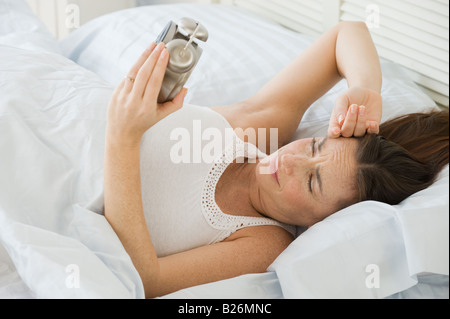 Hispanic Frau betrachten Wecker Stockfoto