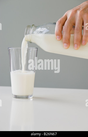 Man gießt Milch in Glas Stockfoto