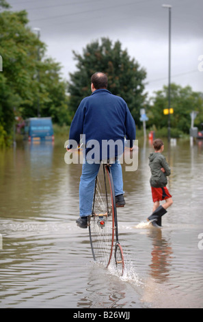 TEWKESBURY RESIDENT GRAHAM WEATHERLY REITET AUF SEINEM HOCHRAD DURCH DAS WASSER WÄHREND DES HOCHWASSERS IN GLOUCESTERSHIRE JULI 2007 U Stockfoto