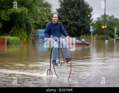 TEWKESBURY RESIDENT GRAHAM WEATHERLY REITET AUF SEINEM HOCHRAD DURCH DAS WASSER WÄHREND DES HOCHWASSERS IN GLOUCESTERSHIRE JULI 2007 U Stockfoto