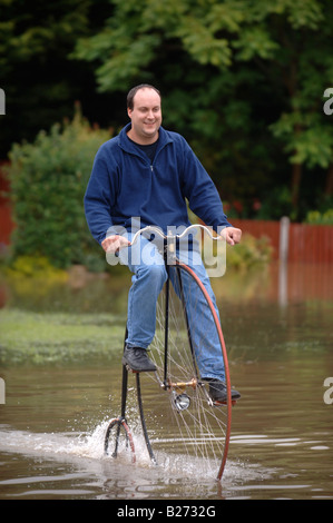 TEWKESBURY RESIDENT GRAHAM WEATHERLY REITET AUF SEINEM HOCHRAD DURCH DAS WASSER WÄHREND DES HOCHWASSERS IN GLOUCESTERSHIRE JULI 2007 U Stockfoto