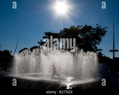 In einem Brunnen Silhouette gegen die Sonne spielendes Kind Stockfoto