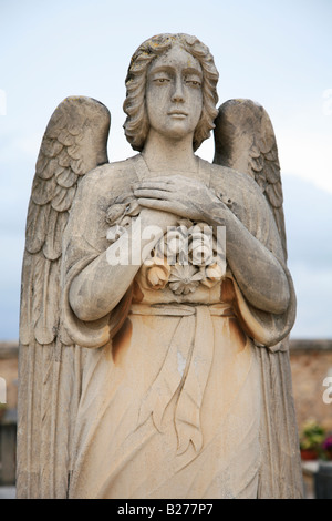 Statue eines weiblichen Engels machte der Orange farbige Stein den Engel hält einen Blumenstrauß gegen ihre Brust. Stockfoto