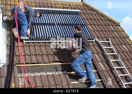 Zwei solar Heizung Ingenieure installieren Platten, Wärme Warmwasser auf dem Dach einer Immobilie in Dorset Stockfoto