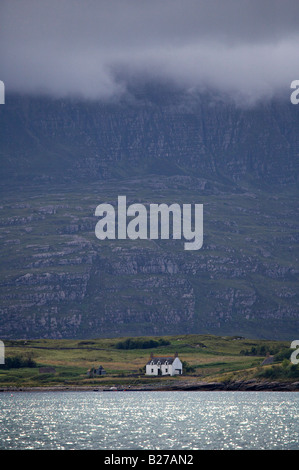 Kleines Häuschen unter einem Berg und stürmischen Himmel Stockfoto