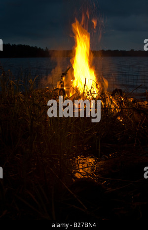 Funken von einer Scheiterhaufen Fliege gegen die brütende Himmel in der Verdunkelung finnische Nacht Stockfoto