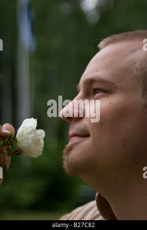 Ein Mann riecht den Duft der weißen rose Stockfoto