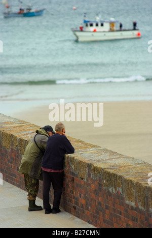 Zwei alte kornische Fischer stehen am Kai in der kornischen Angeln Stadt von Newquay in England Boote im Hintergrund sprechen Stockfoto