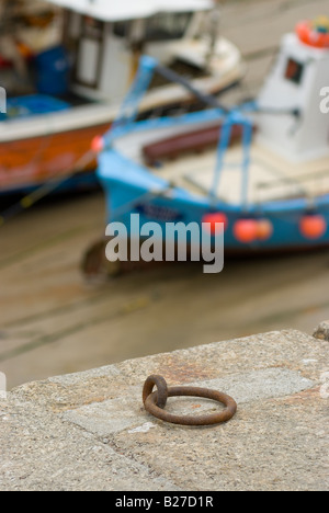 Stillleben mit einem Liegeplatz Ring scharf mit Fischerbooten im Hintergrund in der Fischerei Hafen von Newquay England gedreht Stockfoto