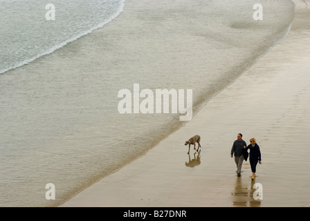 Urlauber Fuß ihren Hund an einem Strand mit sanft plätschernden Wellen in Newquay Cornwall England Stockfoto