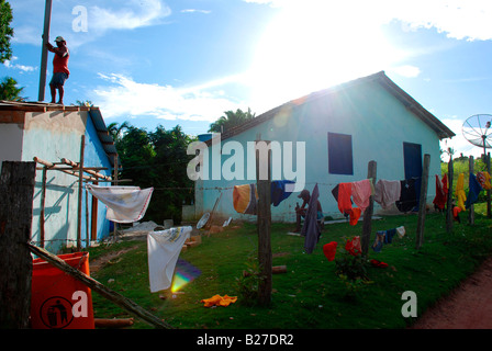 Ein Mann Befestigung das Dach seines Hauses und Wäsche hängen auf dem Zaun in einem Indianer-Reservat Stockfoto