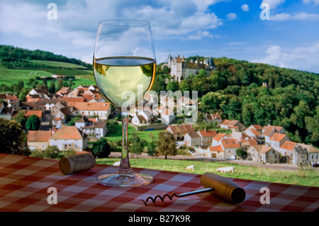 Weißer Chardonnay Wein & Glaskorken & Korkenzieher auf typisch französisch karierte Picknick-Tischdecke, mit Dorf und Chateau de la Rochepot dahinter, Burgund Stockfoto