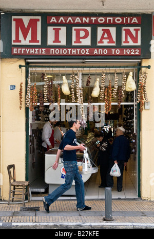 Ein Kellner trägt ein Tablett mit Kaffee Frappe vorbei an einem Delicsatessen Geschäft in Evripidhou Straße im Zentrum von Athen Stockfoto