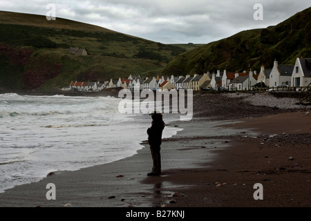 Die berühmte Küste Dorf von Pennan, Aberdeenshire, Schottland, UK, mit einen Mann stehen am Strand in der Abenddämmerung Stockfoto