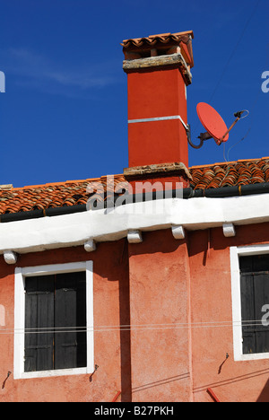 Roten Parabolantenne auf roten Schornstein des alten Hauses gegen blauen Himmel Stockfoto