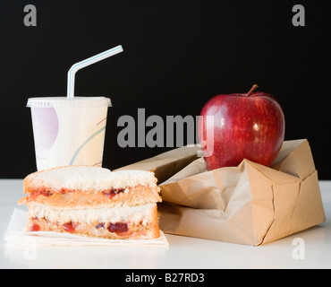 Sandwich, Apfel und Getränk neben Papiertüte Stockfoto