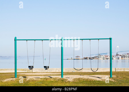 Eine Schaukel auf einem öffentlichen Spielplatz in Wellington Avenue mit Blick auf den Hafen von Newport und Newport Bridge im Hintergrund Stockfoto