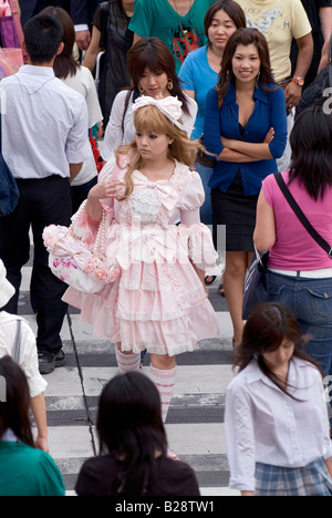 Eine Mädchen gekleidet Rüschen Lolita-Stil ist Fuß in einer Menschenmenge überqueren einer viel befahrenen Straße in Tokio Stockfoto