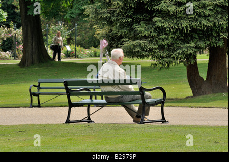 Menschen im Park: Ein älterer Mann sitzt auf einer Sitzbank in Sheffield Botanical Gardens in tiefer Kontemplation. Stockfoto