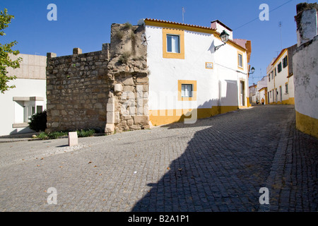 Straße von Crato mit Blick auf die alte Schlossmauer, die von den alten Häusern verwendet. Crato, Portalegre, Alentejo, Portugal. Stockfoto