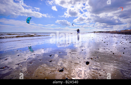 Kitesurfer, die auf nassen Sandstrand Silhouette gegen den Himmel. Bild von Jim Holden. Stockfoto