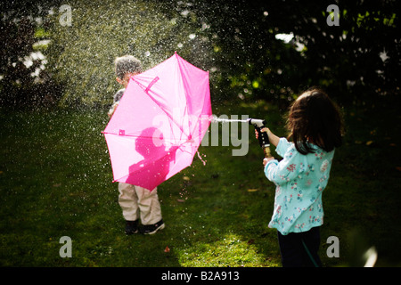 Jungen im Alter von sechs Jahren Unterstände hinter rosa Regenschirm Stockfoto