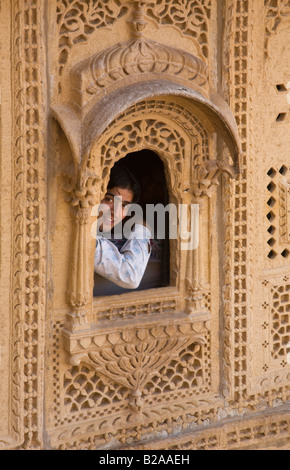 Ein indischer Junge blickt eine handgeschnitzte Sandstein, die Fenster in der Maharadscha Palast in JAISALMER FORT RAJASTHAN Indien befindet sich Stockfoto