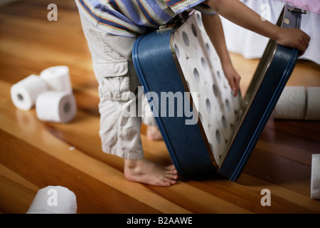 Sechs Jahre alter Junge packt Toilettenpapierrollen in Koffer Mischlinge indischen ethnischen und kaukasischen Stockfoto