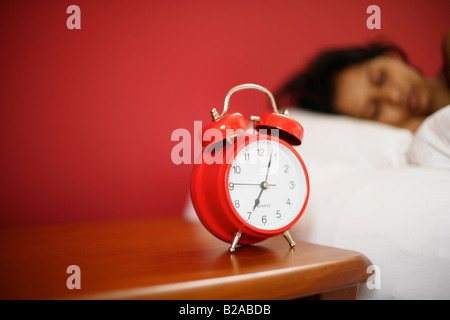 Indische Frau 30er Jahre schläft neben Wecker Stockfoto