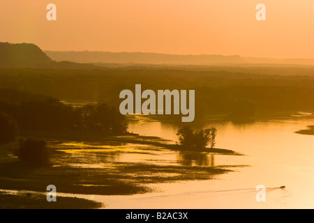 Ein einzelnes Boot bewegt sich auf dem Mississippi als das Wasser die letzten Strahlen der Sonne fängt. Stockfoto