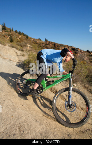 Weiblich-Mountainbiker fährt bergab unter trockenen Bedingungen Stockfoto