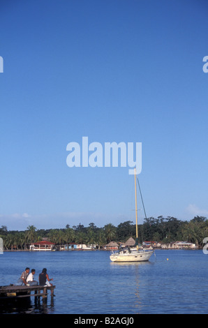 Drei junge schwarze Leute sitzen auf einem Pier in der Stadt von Bocas del Toro, Isla Colon, Panama Stockfoto