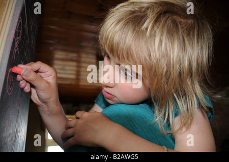 Junges Kind an Tafel schreiben Stockfoto