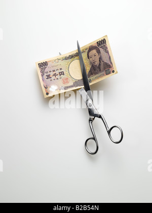 Schere schneiden japanische Yen Geld auf weißem Hintergrund Stockfoto