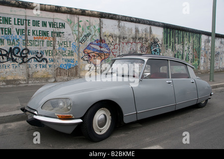 Ein altes Fahrzeug des neuen Autos, das neben der Gedenkstätte der East Side Gallery auf dem verbleibenden Teil der Berliner Mauer geparkt ist. Deutschland Stockfoto