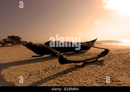 Traditionellen hölzernen Fischerboot liegt am Sandstrand von Cavelossim Beach bei Sonnenuntergang Süd-Goa Indien Stockfoto