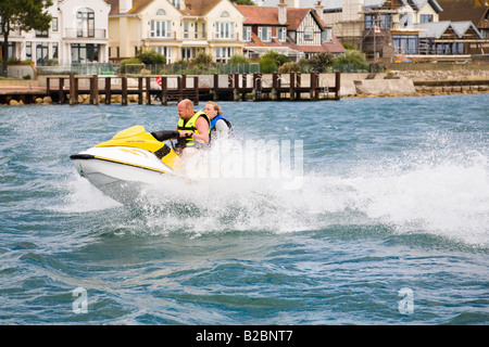 Menschen Jetski vor den teuren Strandpromenade Eigenschaften auf Sandbänken, Poole, Dorset. UK Stockfoto