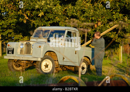 Arbeiter in insgesamt einen Holz-Balken in den hinteren Teil eines historischen 1963 Landrover Serie 2a Truckcab im Laden sehr originell und... Stockfoto