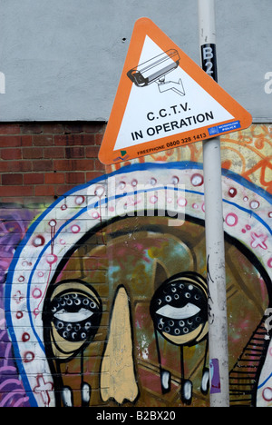 Polizei CCTV-Zeichen und eine "Sweet Toof Wandgemälde ("Burning Candy") im Hintergrund, London Stockfoto