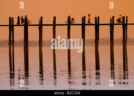 Radfahrer und Fußgänger überqueren die U Bein Brücke bei Sonnenuntergang, alten hölzernen Teak zu überbrücken, Mandalay, Myanmar, Südostasien Stockfoto