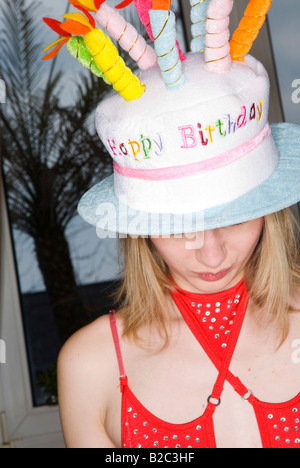 junge Frau mit einem Hut wie eine Geburtstagstorte, alles Gute zum Geburtstag Stockfoto