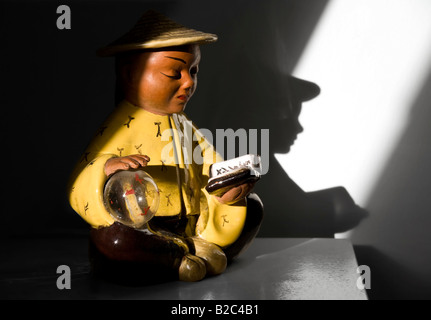 Chinesische Figur, Keramik Figur in einer rauen Lichtstreifen, lesen, Schatten Stockfoto