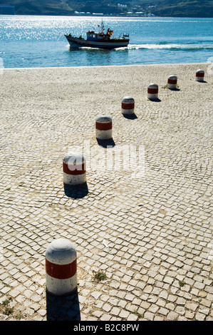 Kleines Fischerboot wie es geht einen großen gepflasterten Kai auf seinem Weg aus dem Hafen am Fluss Tejo in Lissabon Portugal Stockfoto
