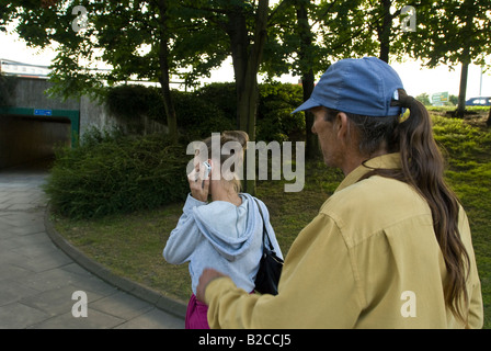 Weißen männlichen Angreifer Tassen junge weiße weibliche Opfer von ihrem Handy Stockfoto