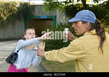 Weißen männlichen Angreifer Tassen junge weiße weibliche Opfer von ihrem Handy Stockfoto