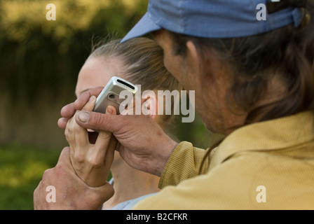 Weißen männlichen Angreifer Tassen junge weiße weibliche Opfer von ihrem Handy Stockfoto